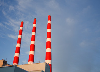 Red and white industrial plant emission stacks.
