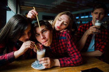 Group of young friends hanging out at a coffee shop. Young men and women meeting in a cafe having fun and drinking coffee. Lifestyle, friendship and urban life concepts.