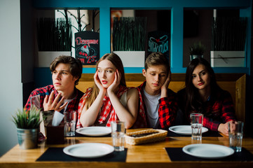 Group of young friends hanging out at a coffee shop. Young men and women meeting in a cafe having fun and drinking coffee. Lifestyle, friendship and urban life concepts.
