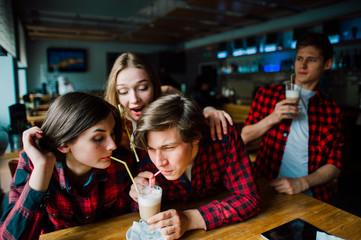 Group of young friends hanging out at a coffee shop. Young men and women meeting in a cafe having fun and drinking coffee. Lifestyle, friendship and urban life concepts.
