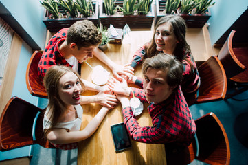 Group of young friends hanging out at a coffee shop. Young men and women meeting in a cafe having fun and drinking coffee. Lifestyle, friendship and urban life concepts.