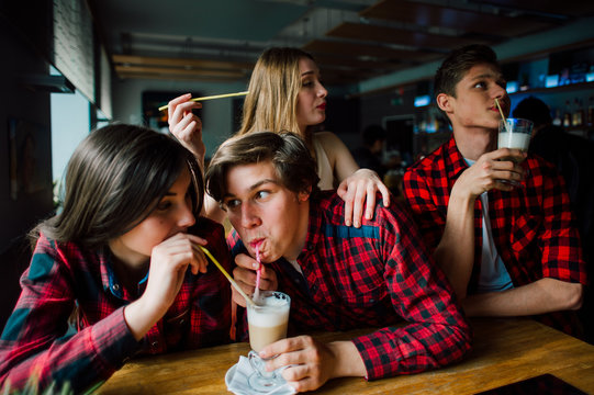 Group of young friends hanging out at a coffee shop. Young men and women meeting in a cafe having fun and drinking coffee. Lifestyle, friendship and urban life concepts.