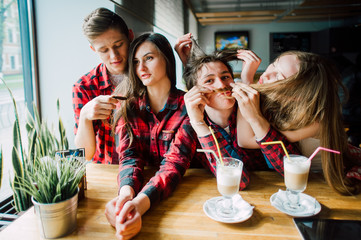 Group of young friends hanging out at a coffee shop. Young men and women meeting in a cafe having fun and drinking coffee. Lifestyle, friendship and urban life concepts.