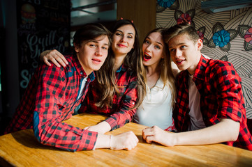 Group of young friends hanging out at a coffee shop. Young men and women meeting in a cafe having fun and drinking coffee. Lifestyle, friendship and urban life concepts.