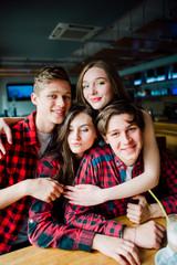 Group of young friends hanging out at a coffee shop. Young men and women meeting in a cafe having fun and drinking coffee. Lifestyle, friendship and urban life concepts.