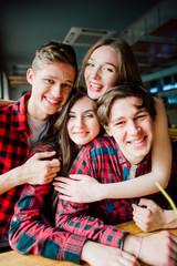 Group of young friends hanging out at a coffee shop. Young men and women meeting in a cafe having fun and drinking coffee. Lifestyle, friendship and urban life concepts.