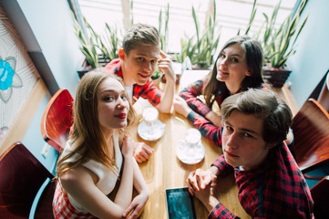 Group of young friends hanging out at a coffee shop. Young men and women meeting in a cafe having fun and drinking coffee. Lifestyle, friendship and urban life concepts.
