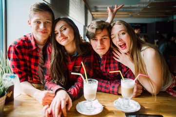 Group of young friends hanging out at a coffee shop. Young men and women meeting in a cafe having fun and drinking coffee. Lifestyle, friendship and urban life concepts.