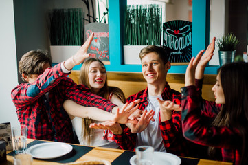 Group of young friends hanging out at a coffee shop. Young men and women meeting in a cafe having fun and drinking coffee. Lifestyle, friendship and urban life concepts.