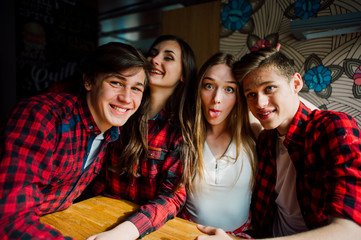 Group of young friends hanging out at a coffee shop. Young men and women meeting in a cafe having fun and drinking coffee. Lifestyle, friendship and urban life concepts.