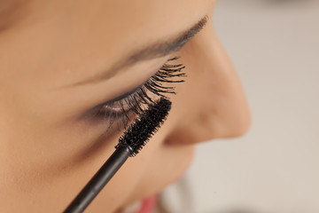 young woman applied mascara to her lashes