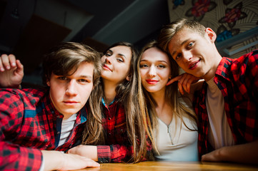 Group of young friends hanging out at a coffee shop. Young men and women meeting in a cafe having fun and drinking coffee. Lifestyle, friendship and urban life concepts.