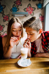 Group of young friends hanging out at a coffee shop. Young men and women meeting in a cafe having fun and drinking coffee. Lifestyle, friendship and urban life concepts.