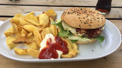 Tasty burger with potato wedges, ketchup and mayonnaise