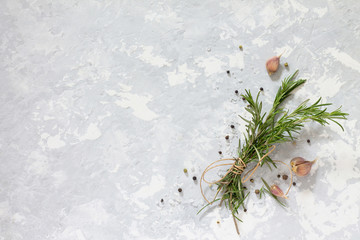 Sprigs of rosemary tied with string and garlic on a gray stone b