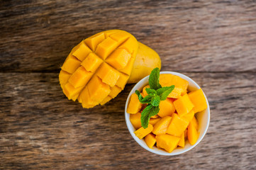 Mango fruit and mango cubes on the wooden table.