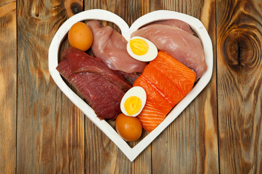 Proteins, Fish, Cheese, Eggs, Meat, Chicken In A Heart On  Wooden Background