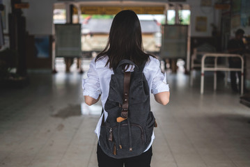 Traveler girl walking and wait train on railway platform.