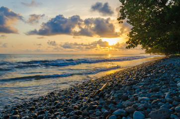 Dramatic coast with rocky volcanic beach, green tree, waves and amazing sunset, Limbe, Cameroon