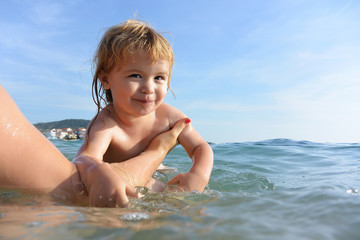 Fototapeta na wymiar Cute little kid swims in water.