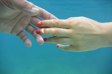 Male and female hands under water.