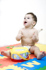 Baby kid playing musical toy. the boy learns to play the drum. A happy smiling 8 month old baby girl is drumming. learning toys at her home. musical toys on white background