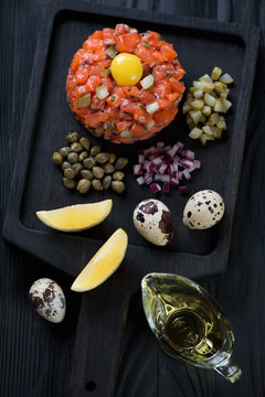 Salmon tartare on a dark wooden serving tray, high angle view