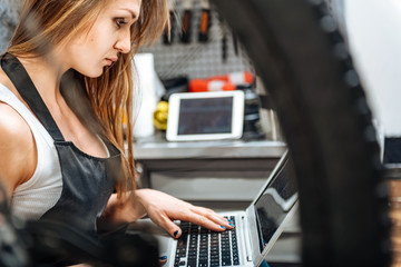 Concentrated female technician using the gadget in the workshop