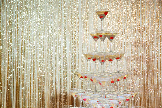 Fototapeta Sparkling champagne pyramid, tower of glasses at the party in front of golden wall