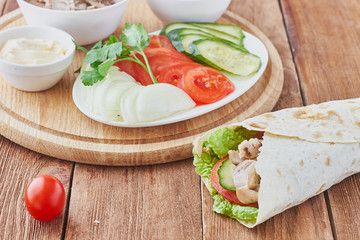 Döner kebab with tomatoes and greens on a wooden background