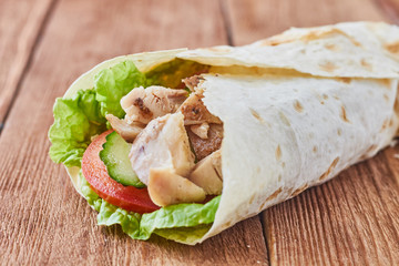Döner kebab with tomatoes and greens on a wooden background