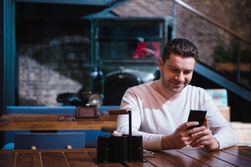 Handsome cheerful man using his smartphone