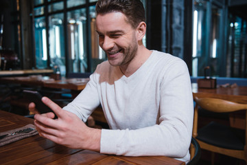 Happy nice man looking at the screen of his smartphone