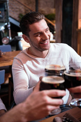 Pleasant smiling man drinking with his friends