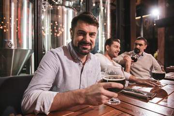 Cheerful nice man putting a glass with beer on the table