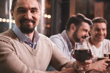 Pleasant joyful man raising his glass