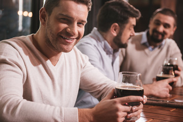 Attractive smiling man sitting with his friends at the table