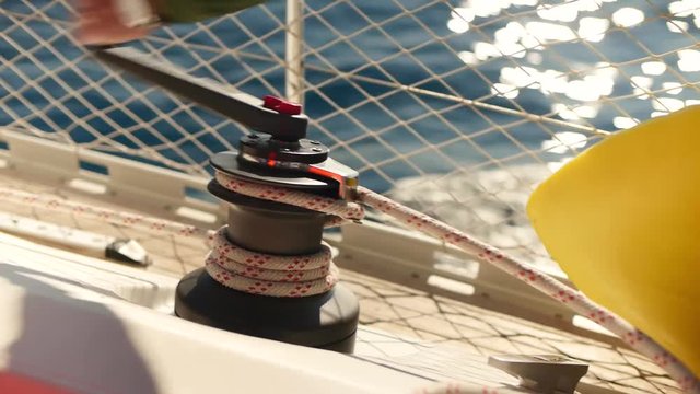 Male hand winding a pulley on a sailboat in the summer sun