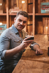 Positive handsome man holding a glass with alcoholic drink