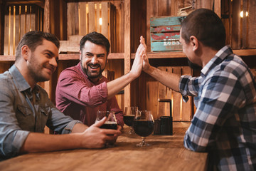 Handsome cheerful friends giving high five