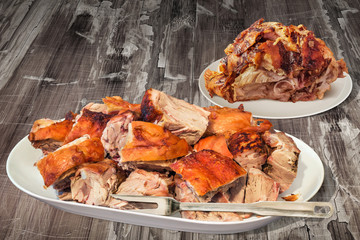 Plateful of Spit Roasted Pork Ham and Shoulder Slices Set on Old Cracked Flaky Wooden Garden Table