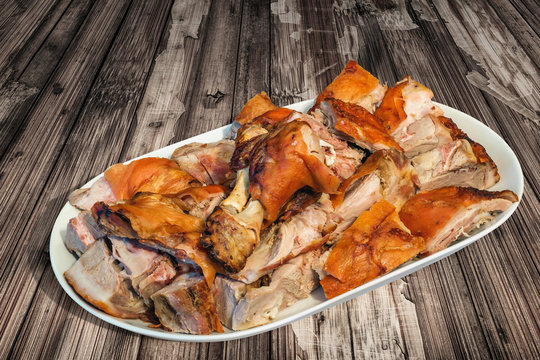 Plateful of Spit Roasted Pork Shoulder Slices Set on Old Cracked Flaky Wooden Garden Table