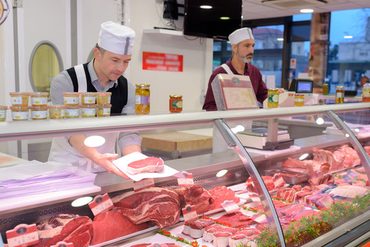 butcher preparing meat behind counter