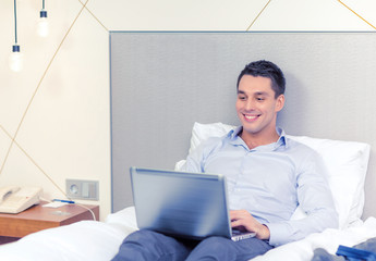 happy businesswoman with laptop in hotel room