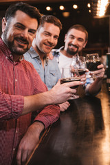 Cheerful delighted men raising their glasses