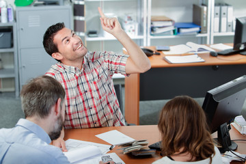 Couple in meting with man who is pointing upwards