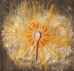 Spaghetti laid creative housewife in the form of the sun on a dark wooden background