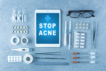 Dermatologist equipment on gray background. Text STOP ACNE on tablet screen