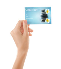 Holiday celebration concept. Female hand with spa service gift certificate on white background