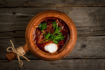 Traditional Ukrainian and Russian meal (soup) - borscht in authentic national dishes. At the rustic wooden table. Top view, copy space